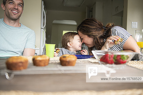 Glückliche Mutter und Tochter reiben sich am Küchentisch die Nasen
