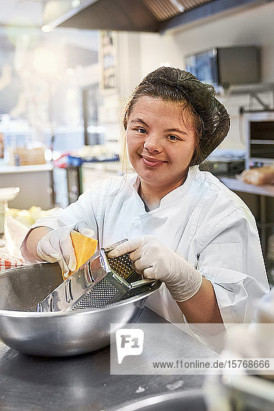 Portrait happy young woman with Down Syndrome working kitchen