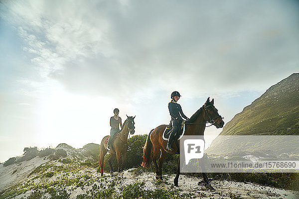 Young women horseback riding on sunny beach