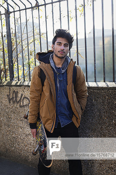 Porträt selbstbewusster junger Mann mit Skateboard