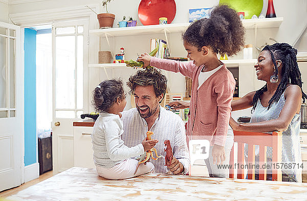 Junge Familie spielt mit Spielzeugdinosauriern in der Küche