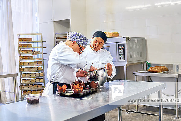 Koch und Student mit Down-Syndrom backen Muffins in der Küche