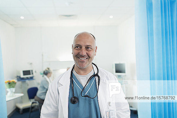 Porträt eines selbstbewussten  lächelnden Arztes in einem Krankenhauszimmer