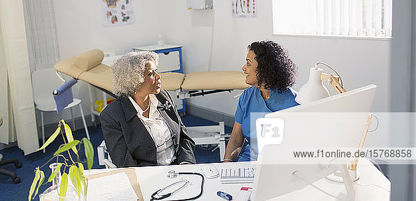 Female doctor talking with senior patient in doctors office