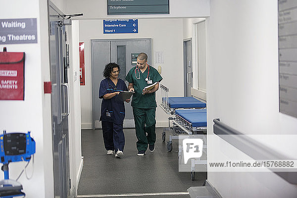 Doctor and surgeon discussing medical chart  walking in hospital corridor