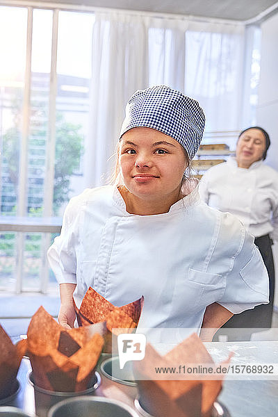 Porträt einer selbstbewussten jungen Frau mit Down-Syndrom beim Backen in der Küche