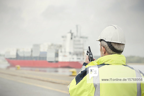 Dockmanager mit Walkie-Talkie bei der Überwachung eines Containerschiffs im Handelsdock