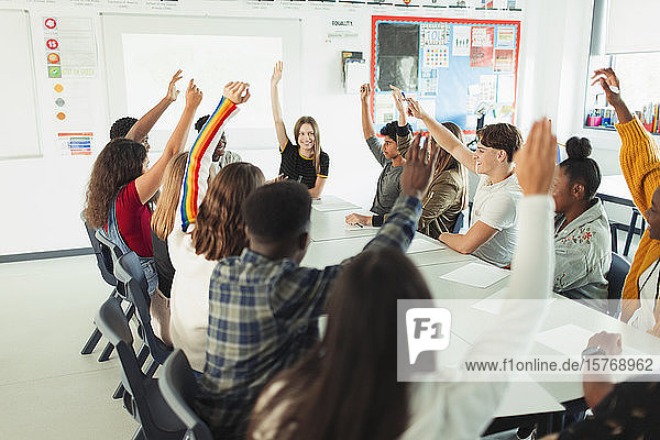 High school students with hands raised in debate class