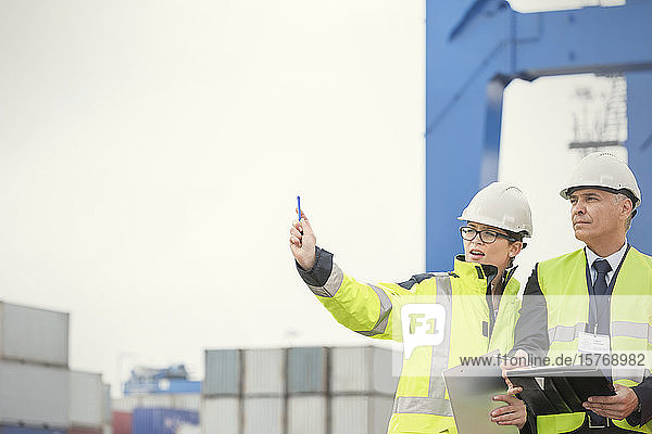 Dockarbeiter und Manager mit Klemmbrett im Gespräch auf einer Werft