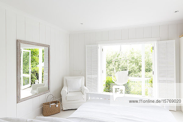 Weißes  ruhiges Musterhaus mit Schlafzimmer  das zur sonnigen Terrasse mit Hängematte führt