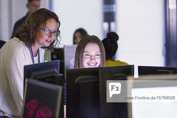 Eine Lehrerin der Junior High hilft einer Schülerin am Computer im Computerraum