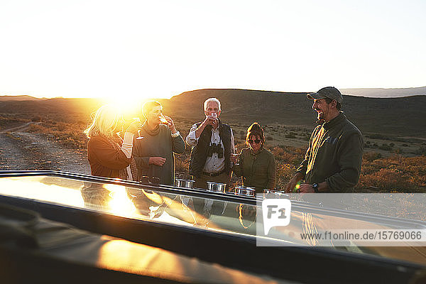 Safari-Gruppe trinkt Champagner bei Sonnenuntergang