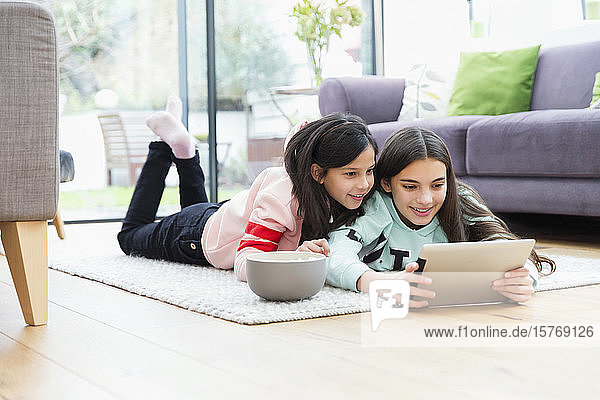 Girls watching movie with digital tablet on living room floor