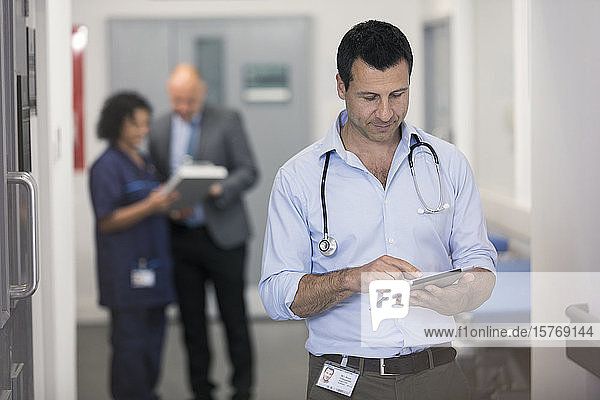 Männlicher Arzt mit digitalem Tablet im Krankenhausflur