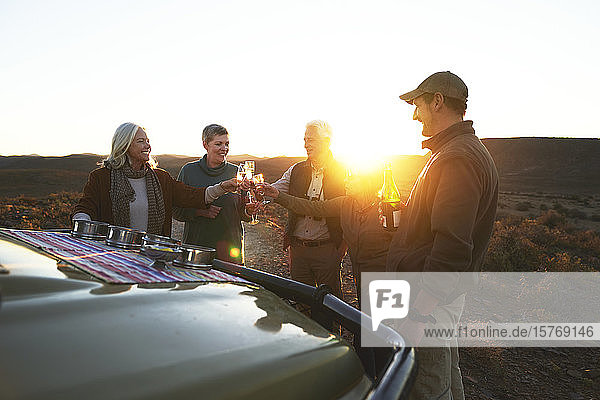 Safari-Gruppe stößt bei Sonnenuntergang mit Champagnergläsern an