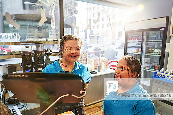 Glückliche junge Frauen mit Down-Syndrom arbeiten in einem Café