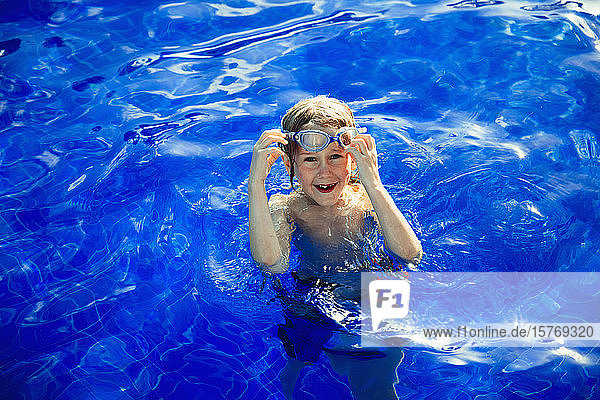 Porträt glücklicher Junge schwimmen in sonnigen blauen Badebuch