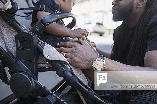 Vater spricht mit Kleinkind im Kinderwagen