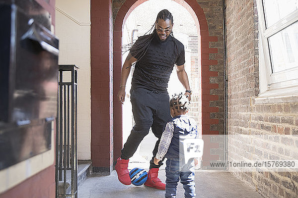 Vater und Kleinkind Sohn spielen mit Fußball im Korridor