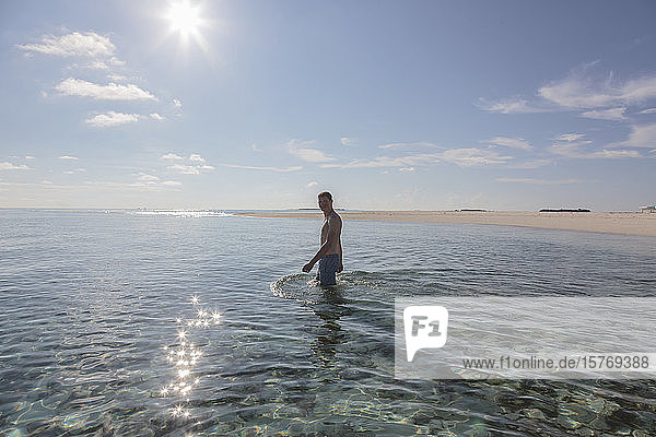 Porträt eines jungen Mannes  der im sonnigen  idyllischen Meer watet  Malediven