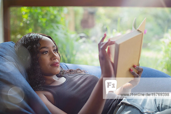 Young woman relaxing reading book in beanbag chair