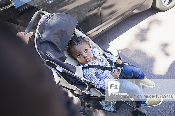 Niedliches Kleinkind im Kinderwagen auf dem Bürgersteig