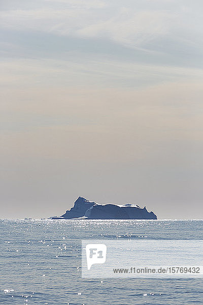 Eisberg in der Ferne auf dem sonnigen  ruhigen Atlantischen Ozean Grönlands