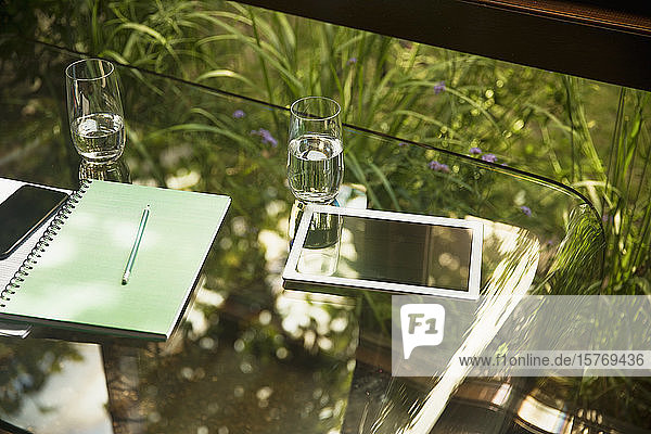Digitales Tablet und Wassergläser auf Glastisch