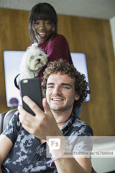 Glückliches junges Paar mit Hund im Videochat mit Smartphone