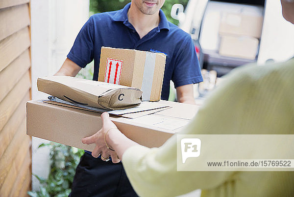 Deliveryman handing packages to woman at front door