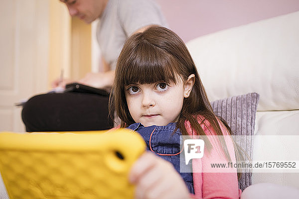 Porträt unschuldiges Mädchen mit digitalem Tablet auf Sofa