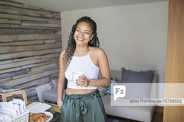 Porträt glückliche junge Frau trinkt Kaffee im Heimbüro