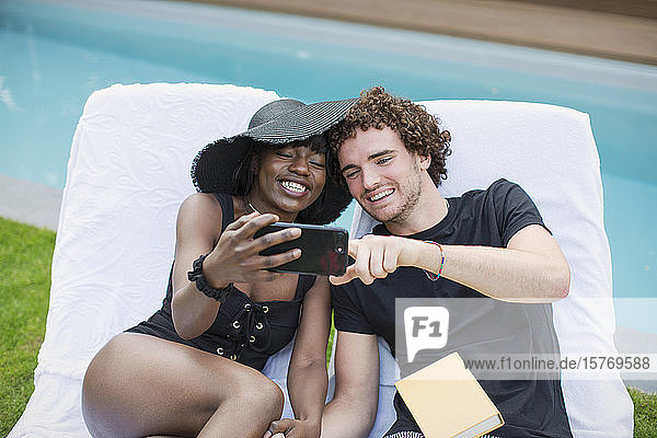 Glückliches junges Paar nimmt Selfie mit Kamera-Handy am Pool