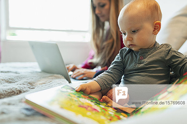 Cute curious baby girl reading picture book