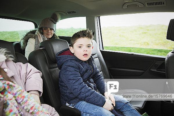 Portrait boy with Down Syndrome riding in back seat of mini van