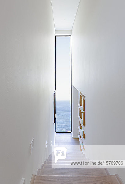 Treppenhaus mit Blick auf ein langes Fenster mit Meerblick in einem modernen  luxuriösen Musterhaus