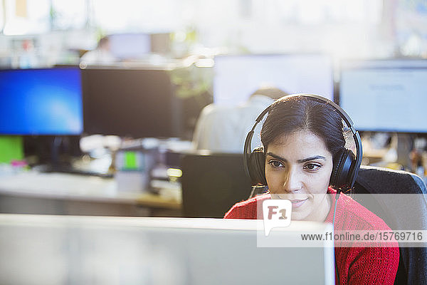 Businesswoman with headphones working at computer in office