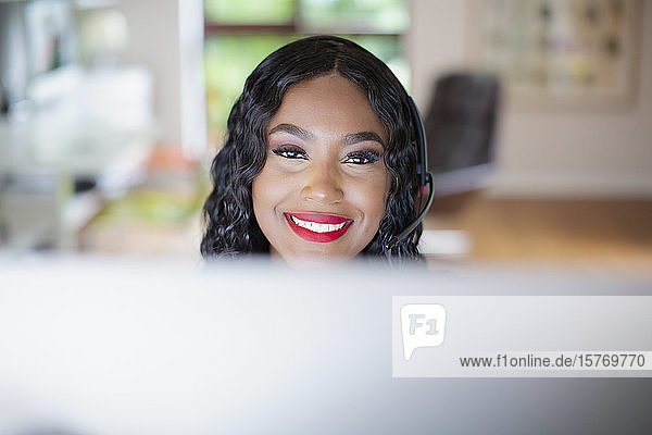 Portrait smiling young woman with headset working at computer