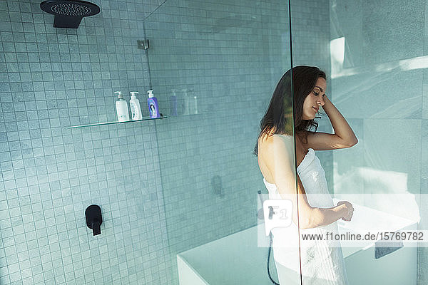 Frau in Handtuch gewickelt in moderner Dusche