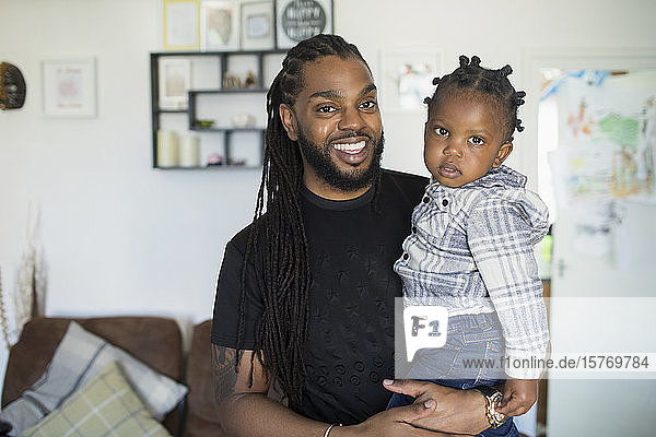 Porträt glücklicher Vater mit langen Zöpfen  der seinen kleinen Sohn im Arm hält