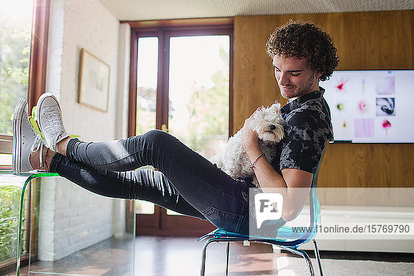Junger Mann streichelt Hund im Heimbüro