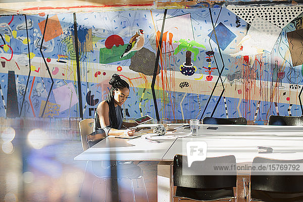 Dedicated creative businesswoman with digital tablet working in conference room