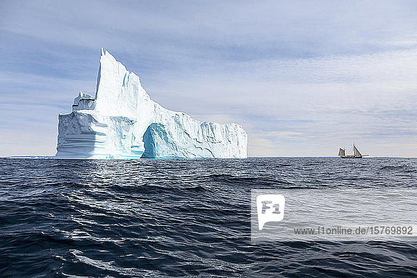 Majestätischer Eisbergbogen über dem sonnigen  ruhigen  blauen Atlantischen Ozean Grönlands