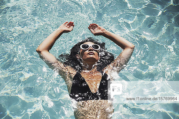 Gelassene Frau schwimmt im sonnigen Sommerschwimmbad