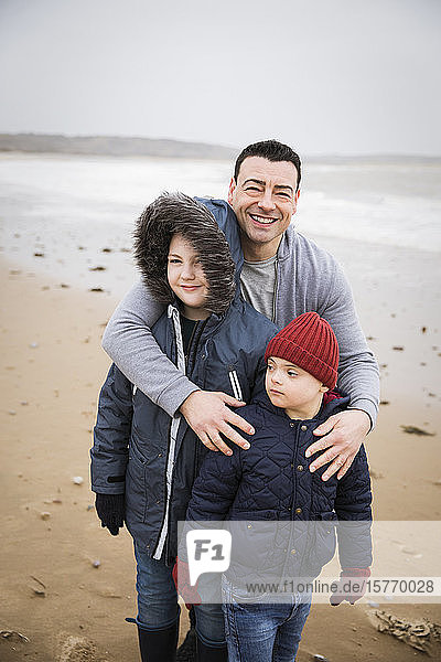 Porträt einer glücklichen Familie mit Down-Syndrom-Kind am Strand