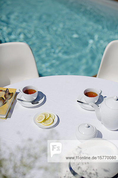 Teeservice auf dem sonnigen Terrassentisch im Sommer am Pool