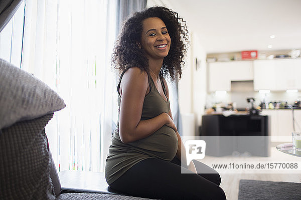 Porträt glückliche junge schwangere Frau reibt Bauch