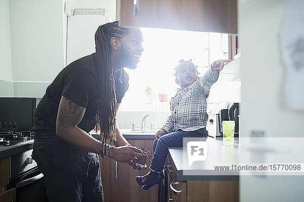 Glücklicher Vater Sohn setzt Schuhe auf Kleinkind Sohn in der Küche