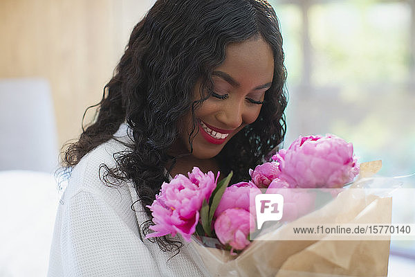 Happy young woman receiving pink peony bouquet