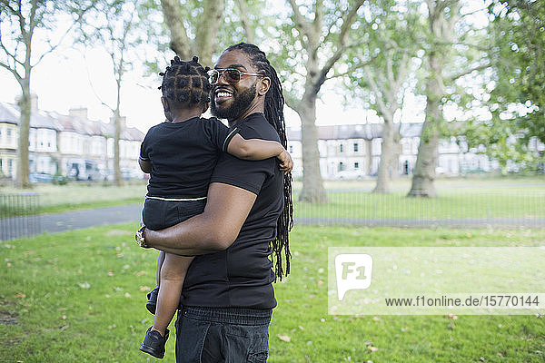 Portrait happy father holding toddler son in park